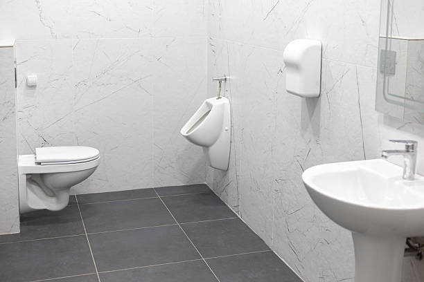 Clean and modern public restroom with white urinal, sink and wc