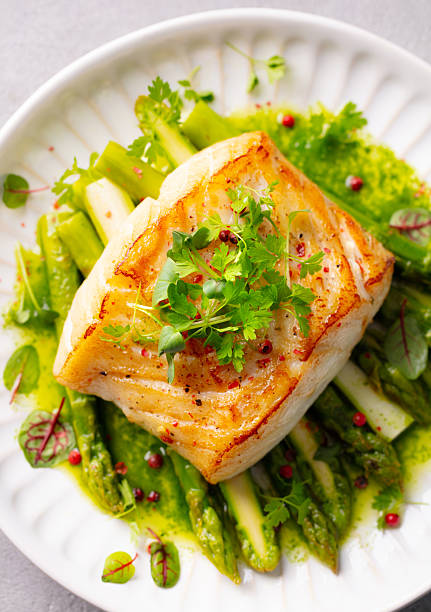 istock Roasted cod with asparagus and on white plate. Close up. Top view. 2218307944