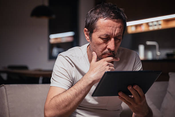 istock Tired exhausted man reading social media content on digital tablet computer at home late at night 2218308617