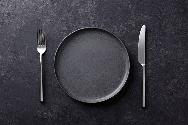 istock Empty black plate with a fork and knife on a dark stone background. Flat lay. Copy space. Top view. 2218308725