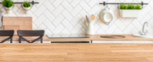 istock Modern kitchen interior with wooden countertop in focus and blurred background elements including utensils, chairs, plants, and white tile wall creating a cozy cooking space 2218310713