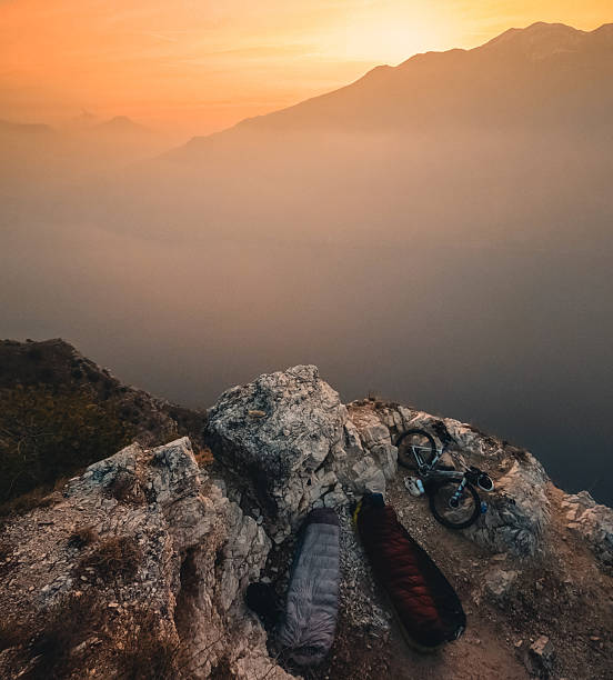 Bivouac camping with bicycles on bluff above lake at sunset, bikepacking around Italy