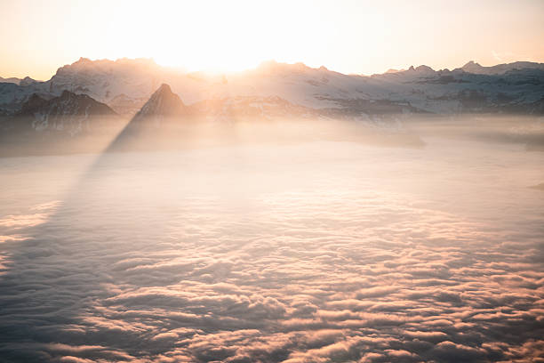 Aerial view of sun rays shining through mountains and clouds, Lucerne Canton, Swiss Alps