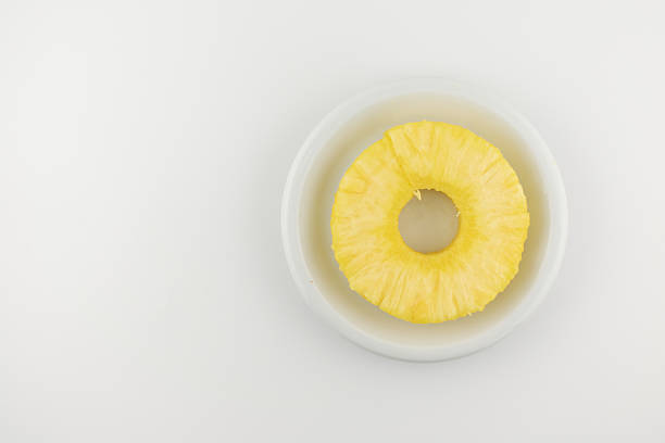 Savor tropical simplicity! This inviting close-up features a perfectly cut pineapple ring centered on a pristine white plate, evoking feelings of refreshing sweetness and healthy delight. Ideal for healthy snacks, fruit platters, or minimalist food photography