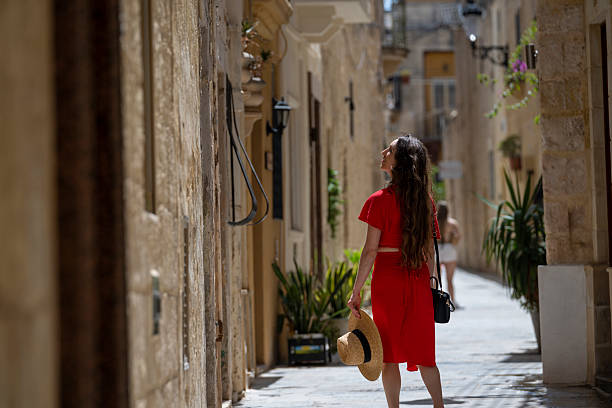 Young woman, wearing red dress, explores colourful, narrow streets in old town, Rabat