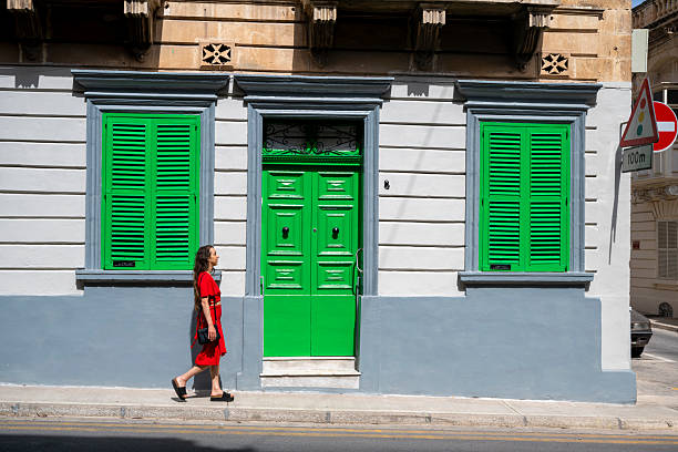Young woman, wearing red dress, explores colourful, narrow streets in old town, Rabat