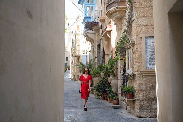 Young woman, wearing red dress, explores colourful, narrow streets in old town, Rabat