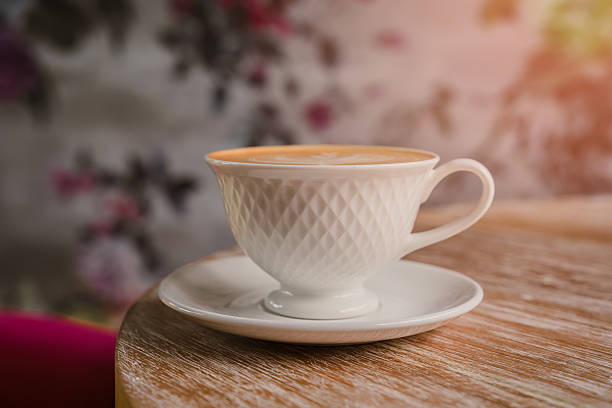 Elegant Cup of Coffee on Wooden Table with Floral Background, Perfect for Coffee Lovers and Aesthetic Enjoyment