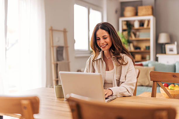 istock Young woman working from home on laptop at dining table 2218322076