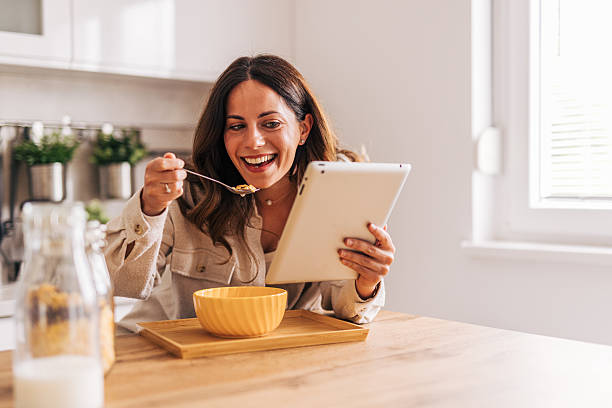 istock Happy woman enjoying breakfast and browsing tablet in kitchen 2218322142