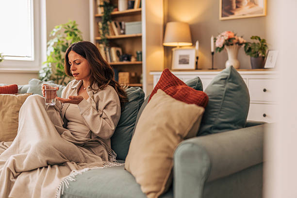 istock Sick woman taking medicine on the sofa at home 2218322443