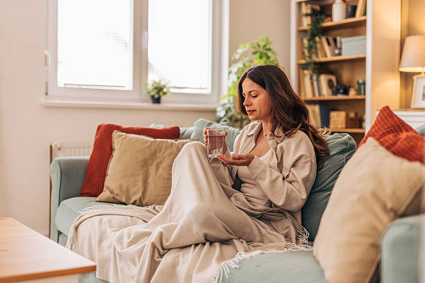 Sick woman taking medicine on the sofa at home