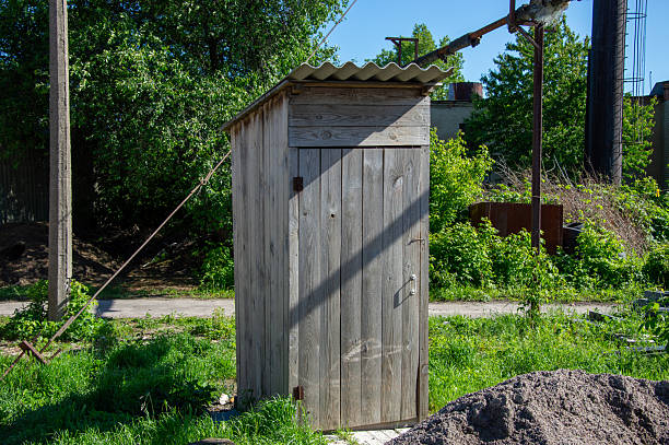 istock A small wooden structure stands alone in a grassy area, surrounded by greenery under a bright blue sky, showcasing a typical daytime scene 2218322544