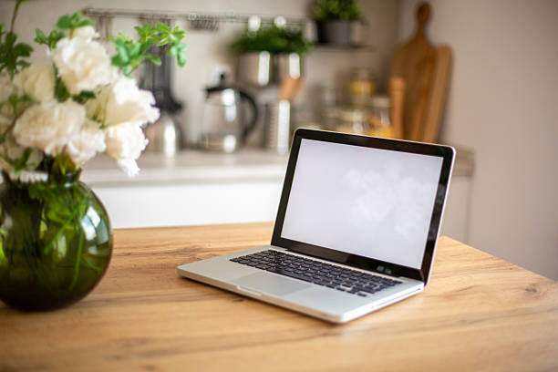 istock Laptop showing blank screen on kitchen table with flowers 2218327769