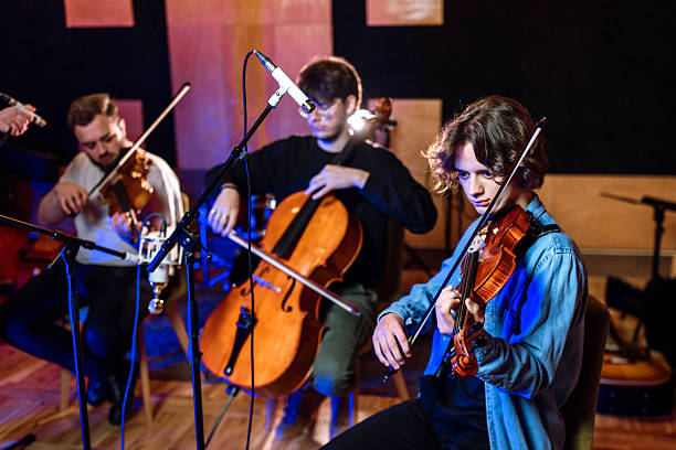 A group of musicians playing cello, viola and violin in audio recording studio.