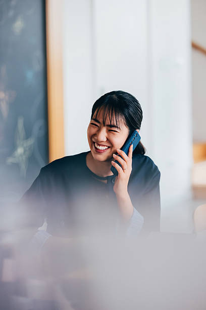 Woman Smiling While Talking on the Phone in a Bright Room
