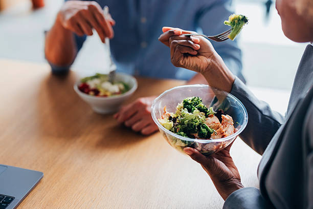 Colleagues sharing a nutritious lunch break in a professional office environment, promoting teamwork and workplace wellness.