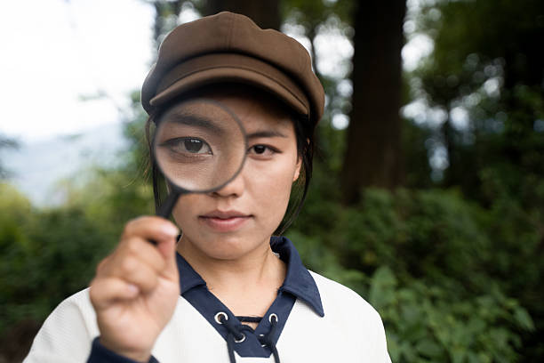 The girl who explores the forest with a magnifying glass, looking at plants and insects
