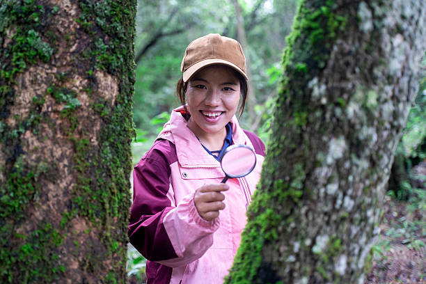 The girl who explores the forest with a magnifying glass, looking at plants and insects