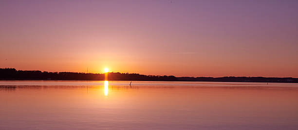 istock Serene lakeside sunrise reflecting warm hues across a tranquil water surface 2218339344