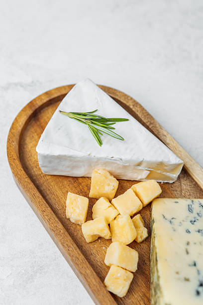 istock Tasty cheese platter with assorted cheeses and fresh herbs on a wooden board 2218340704