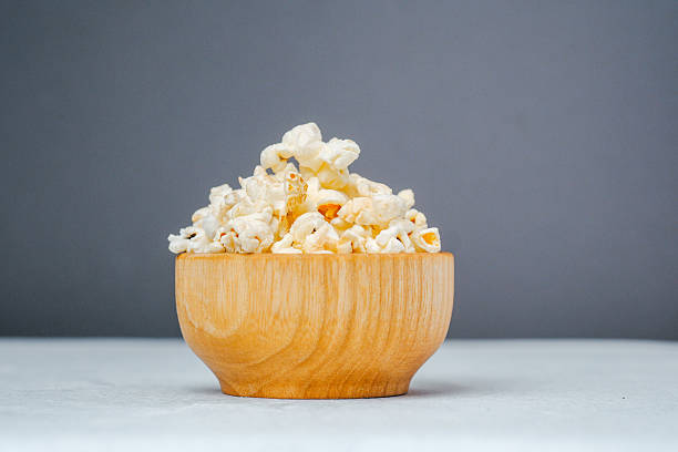 istock Wooden bowl filled with fluffy popcorn against a gray backdrop 2218340730