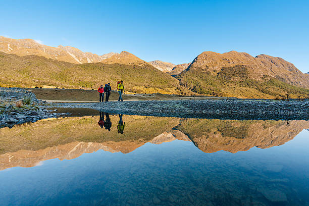 istock Group of hikers walking along a reflective mountain lake trail. 2218343027