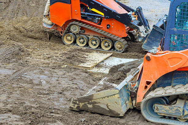 Heavy machinery works on wet ground to prepare construction site for building development under works day