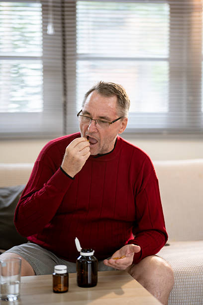 istock An elderly man is sitting and taking medicine in his home. 2218351046