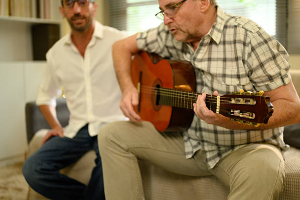 istock Elderly father playing guitar with son at home. Father day concept 2218352091