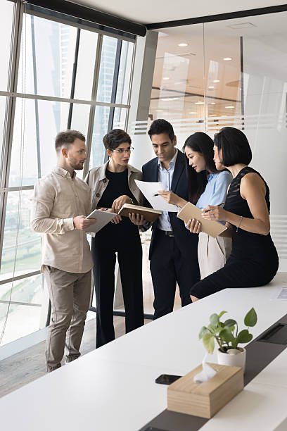 istock Five multinational workmates reviewing business documents in boardroom 2218353491