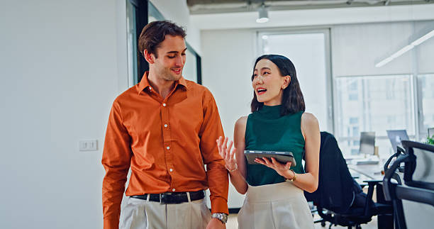 istock Young diverse businesspeople walking work discussing strategy while holding digital tablet in modern office. Sustainable business and finance. 2218354376