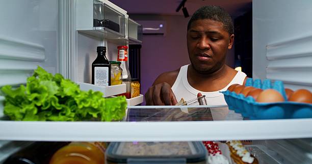 istock A man eats standing near the refrigerator 2218355090