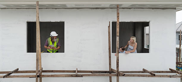 Manual workers cooperating while carrying wood plank at construction site. Blurred motion. Copy space.
