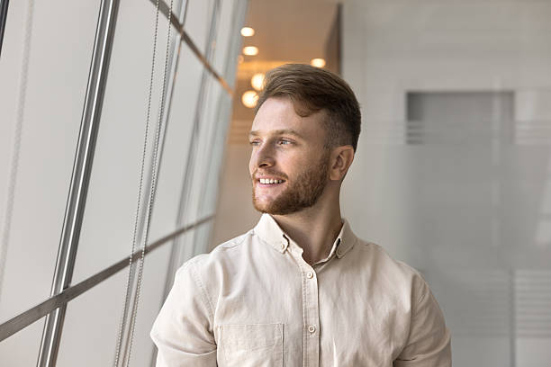 Handsome millennial businessman posing alone in modern workspace