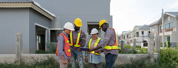 istock Four construction worker gather to discuss plan on tablet computer, stand outside a building site. They wear hardhat and safety vest, focus on their task amid surrounding structure. 2218357212