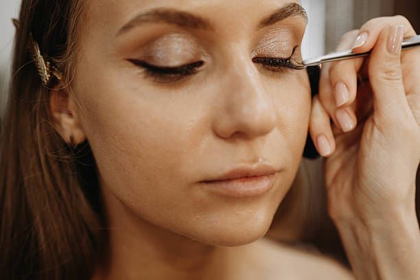 istock Eyelash extensions. Makeup artist applies eyelashes to model eyes 2218359342
