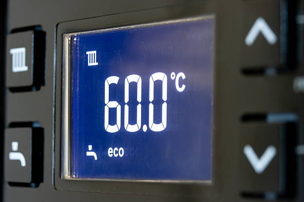 Close-up of grilled sausages on a barbecue with a digital meat thermometer inserted, displaying 90F, showing the meat is still raw and not safe for consumption