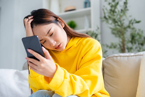 istock Bad news on device screen. Upset asian woman frustrated by problem with work or relationships, sitting on couch, feeling despair and anxiety, loneliness, having psychological trouble 2218360244