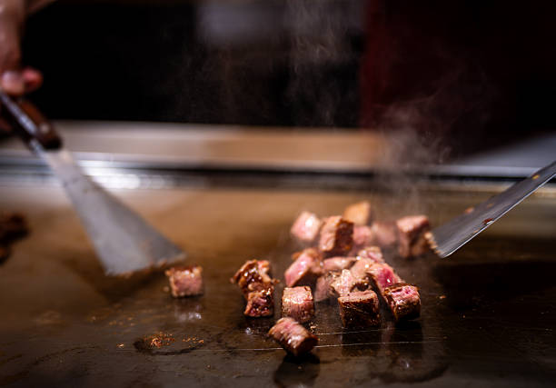 Close-up of succulent wagyu beef cubes being grilled to perfection on a hot teppanyaki plate.