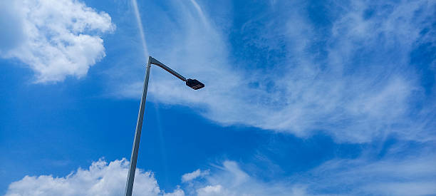 istock Street light pole extending into a bright blue sky with feathery clouds. 2218369860