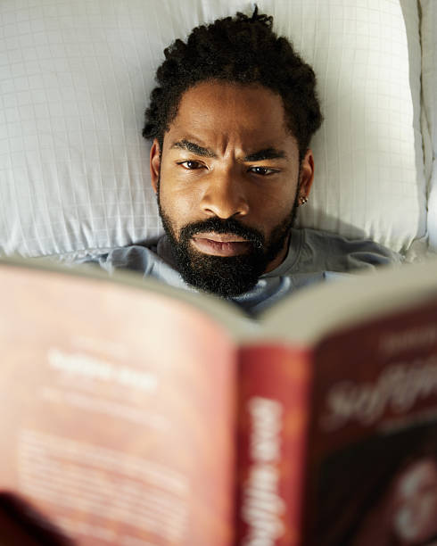 istock Above view of relaxed black man reading a book in bed. 2218373977