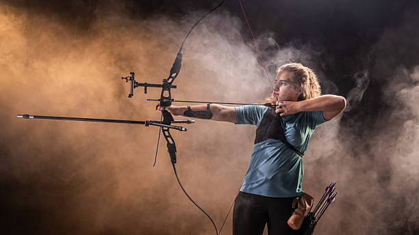 istock Female Archer Release Arrow in Dramatic Smoky Studio Background 2218374456