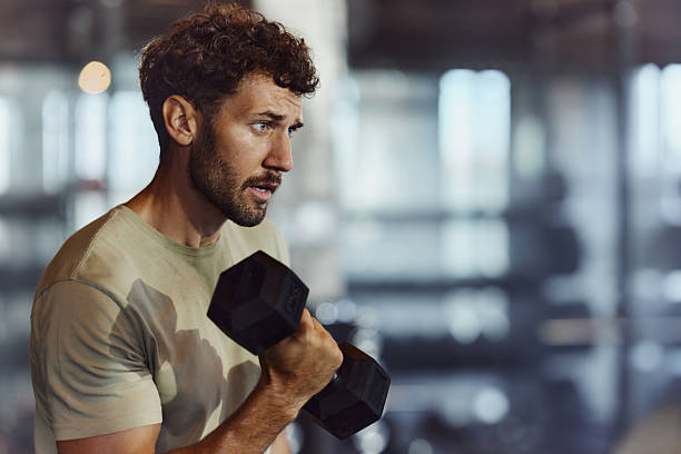 istock Determined male athlete exercising with dumbbells in a gym. 2218374612