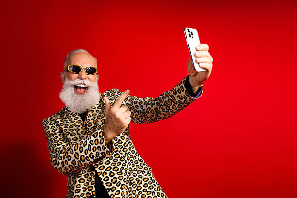 istock Elderly man wearing a leopard print suit taking a selfie against a vibrant red background 2218375921
