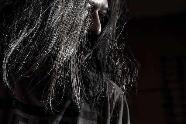 Disheveled Long-Haired Man Staring Seriously in Shadowy Light
