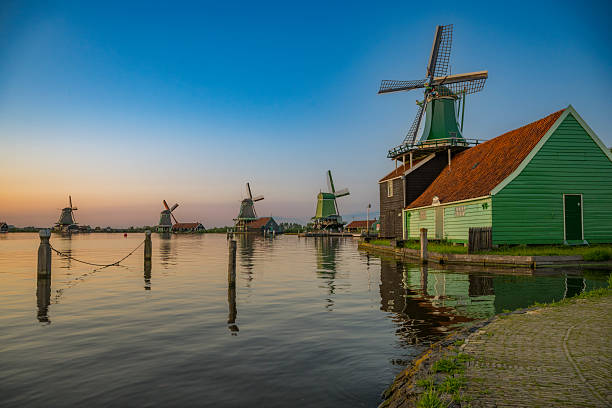 Zaanse Schans windmills along the Zaan river in Zaandam, North Holland, Netherlands, during a summer sunet aerial view. Zaanse Schans is a popular tourist destination in the Netherlands, located in the province of North Holland. It is renowned for its well-preserved historic windmills and houses, showcasing traditional Dutch architecture and craftsmanship from the 18th and 19th centuries.