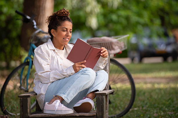 istock Relaxed Woman Smiling While Reading Book in Park. 2218379566