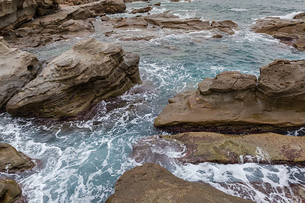 istock Sea surf waves between coastal rocks in overcast rainy weather 2218380702