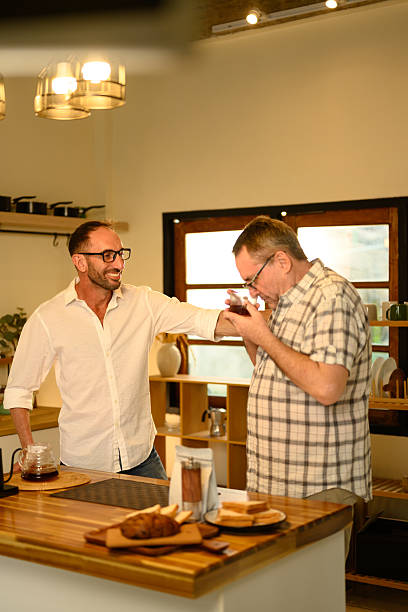 istock Senior man and son making pour over coffee in a cozy kitchen. Father day concept 2218387831